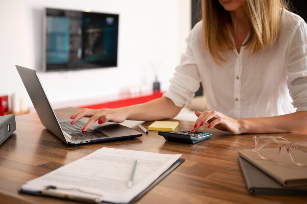 Mulher sentada à mesa com laptop e calculadora